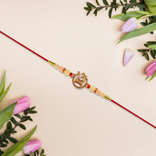 Designer Religious Rakhi With Golden Om And Swastik Motif And Pearl Beads On Red Thread